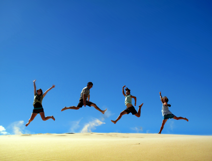 People jumping on sand dune